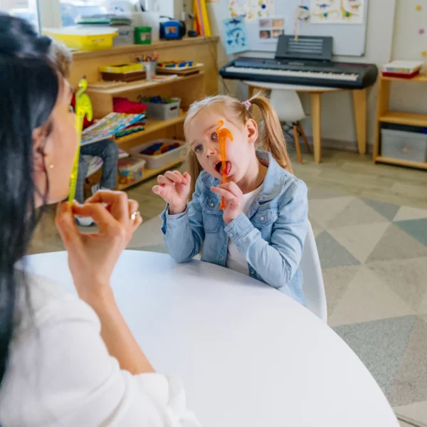 Therapeutin zeigt einem Kind Zungenübungen im Spiegel – Training der Mund- und Zungenmuskulatur.
