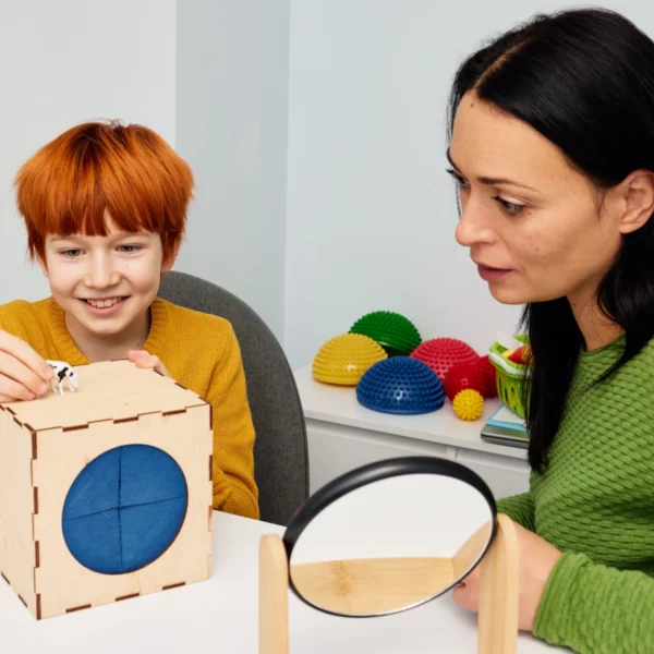 Logopädin arbeitet spielerisch mit einem Kind am Tisch – Förderung der kindlichen Sprachentwicklung.